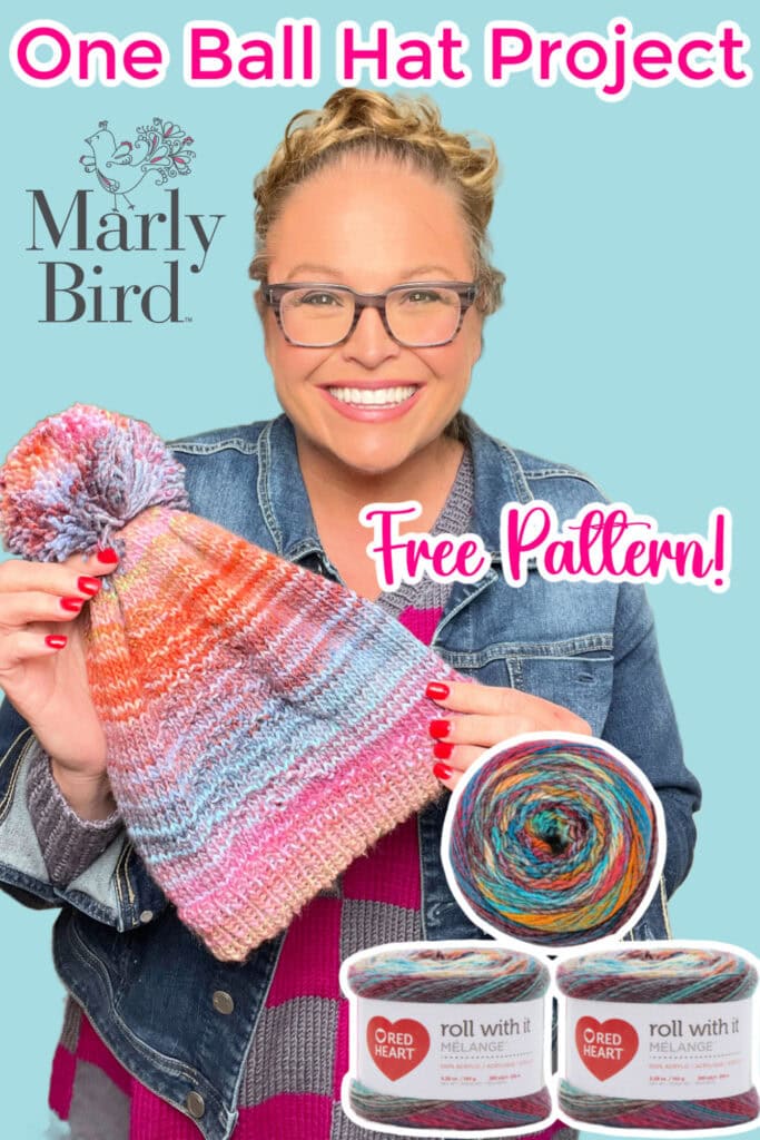A smiling woman with glasses holds up a colorful knit hat with a pom-pom. Text reads "One Ball Hat Project," "Free Pattern!" and shows Red Heart gorgeous yarn skeins and the Marly Bird logo on a blue background. -Marly Bird