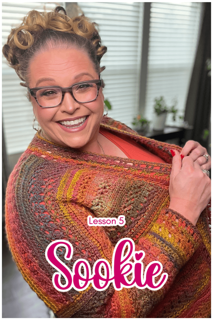 A person wearing glasses smiles while wrapped in a colorful, intricately patterned shawl. The text on the image reads "Lesson 5 Sookie." The background features windows with blinds and houseplants. -Marly Bird