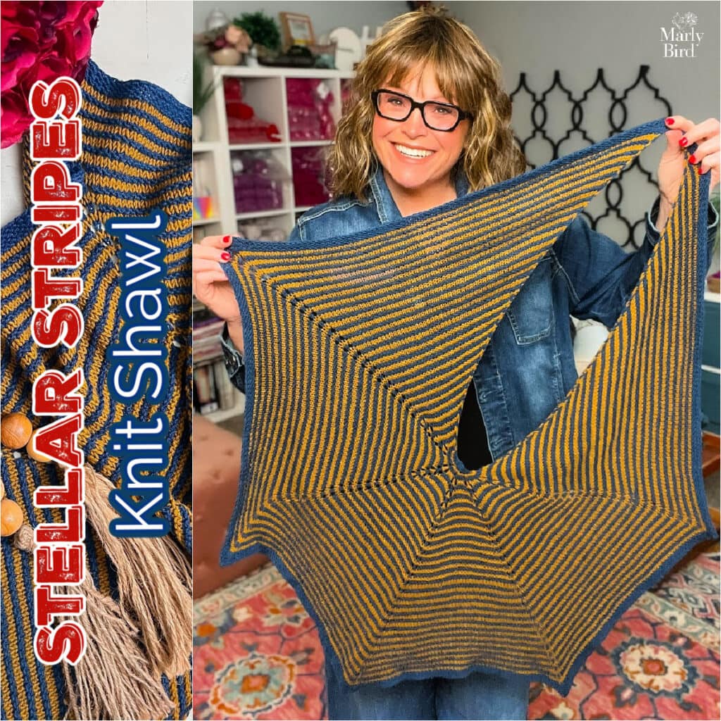 Person holds a blue and gold striped geometric knit shawl, showing its stitch detail; shelves with supplies in background.