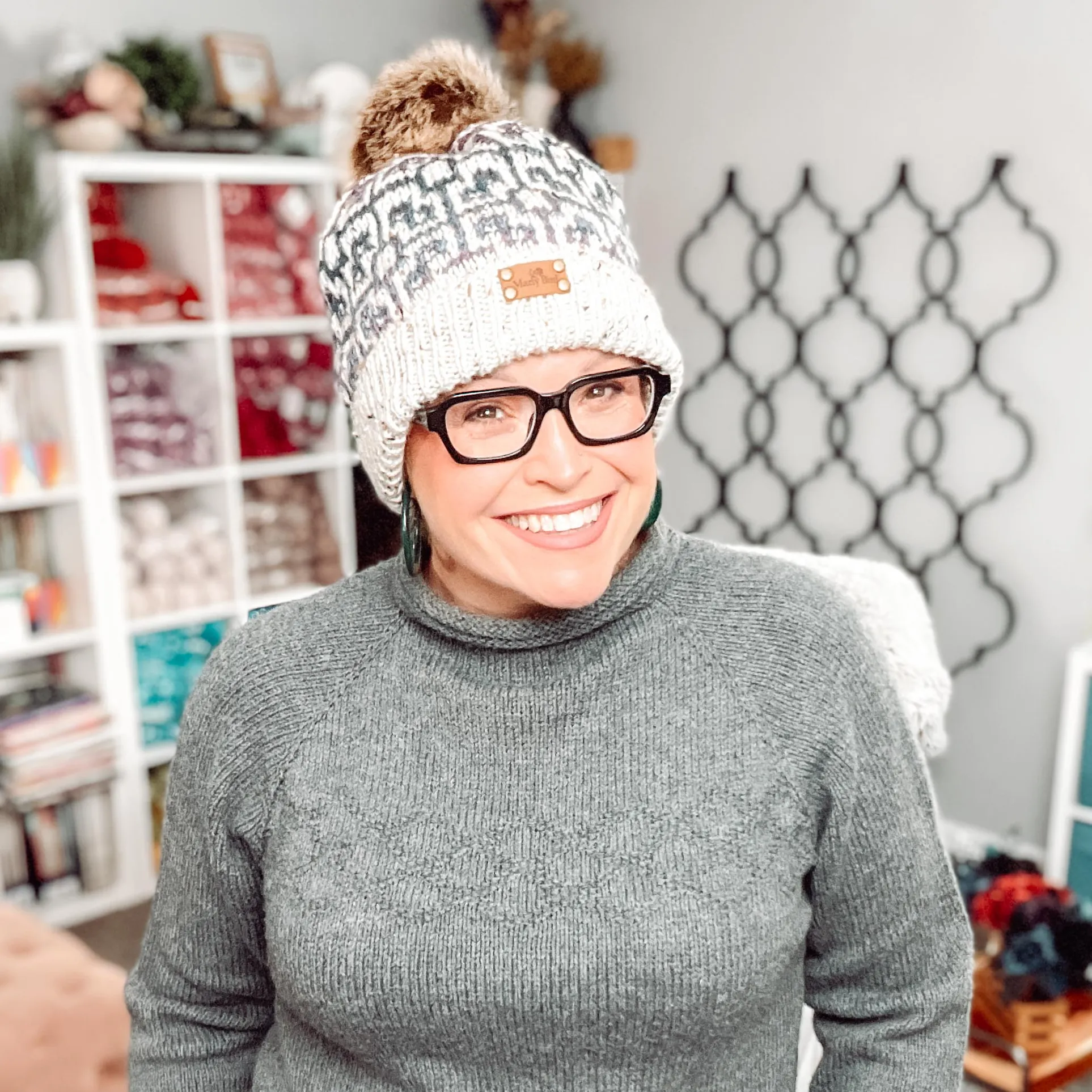 A woman wearing a knit hat and glasses, sporting the cozy style of a Marly Bird Knit Hat Pattern. -Marly Bird