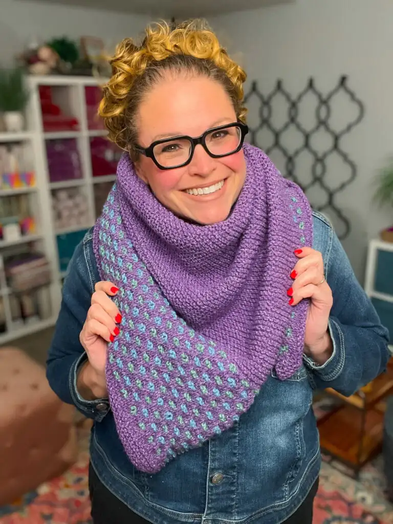 Summit Knit Shawl in purple with blue-green textured pattern, worn over shoulders, showcasing stitch detail indoors. Summit Knit Shawl free garter stitch knit shawl pattern