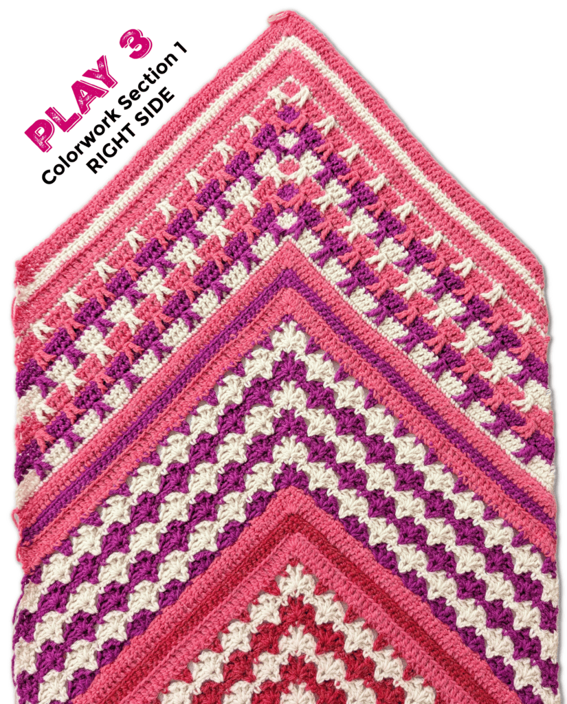 Colorful crochet shawl featuring vibrant pink and purple hues with a textured granny square stitch pattern.