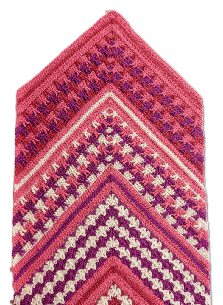 Pink, purple, and cream chevron crochet fabric with textured stitches and bold zigzag rows displayed on a white background.