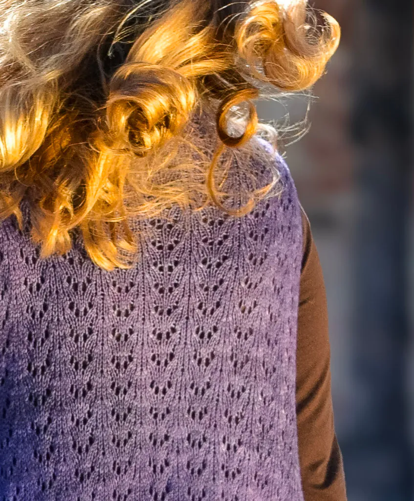 Back view of a person wearing a hand-knit purple lace duster, showing the openwork stitch detail and soft drape.