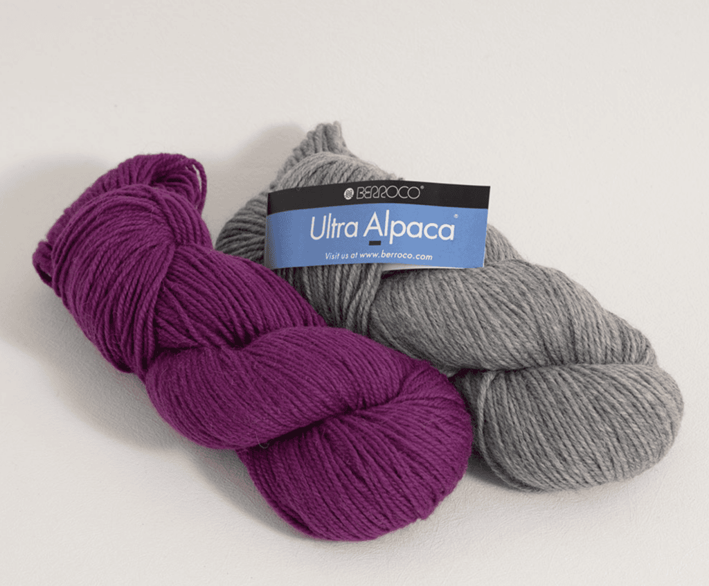 Magenta and light gray yarn skeins on a pale surface; gray labeled "Berroco Ultra Alpaca" for cozy crochet wraps or shawls.