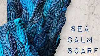 Blue and teal knit scarf with wavy stitch pattern, shown next to “SEA CALM SCARF” text and a seashell on gray fabric.
