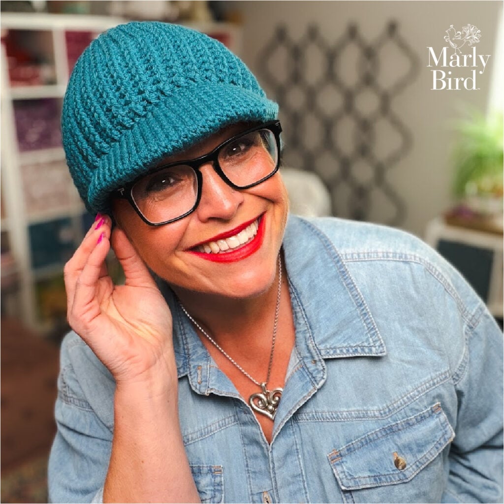 Marly Bird close-up wearing the Ribbed for Him and Her teal ribbed crochet beanie with bill and glasses