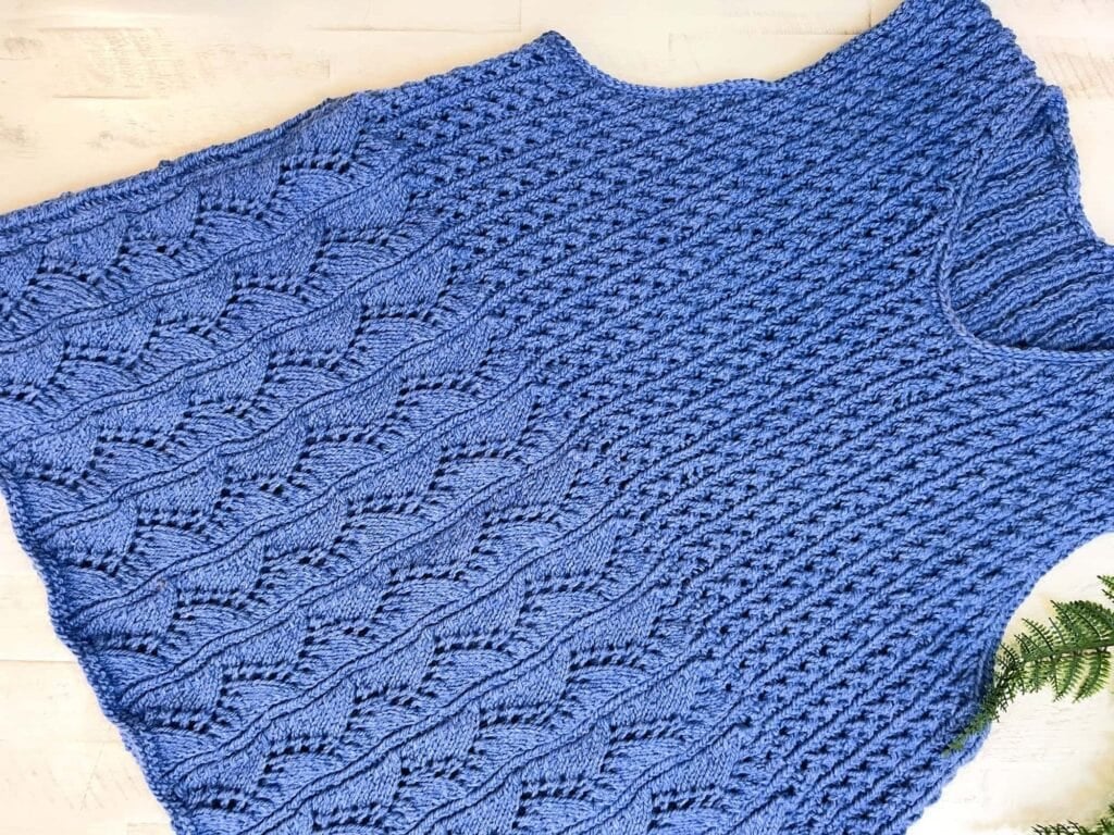 Full-length wearing shot of the Thistlevine free knit tunic vest pattern by Marly Bird, showing the complete A-line peplum silhouette over jeans, sizes XS through 5X