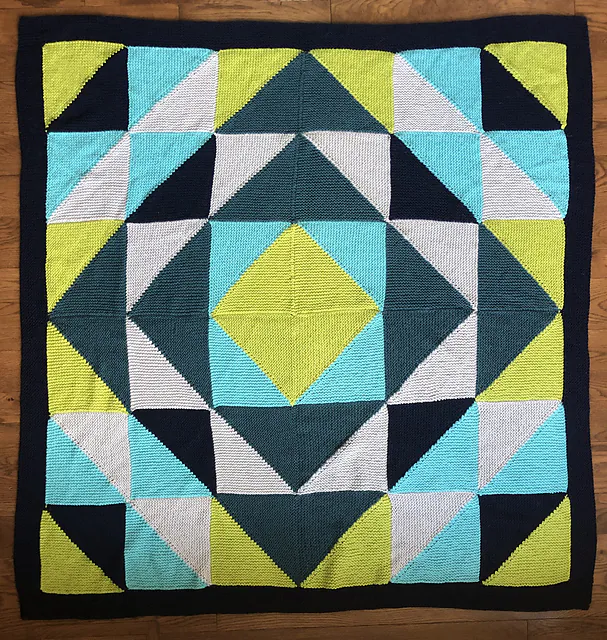 Colorful quilt with triangles and diamonds in teal, navy, lime, yellow, white, and blue; finished with a solid navy border.